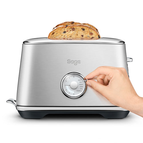 A hand turning the browning dial on Sage the Toast Select Luxe with a slice of fruit loaf in the slot, official view